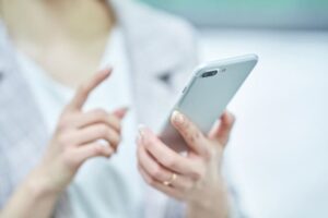 スマホでネット予約を取る女性の写真